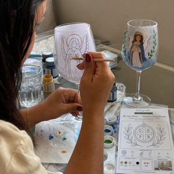 Mujer pintando una copa siguiendo la plantilla dentro del vidrio